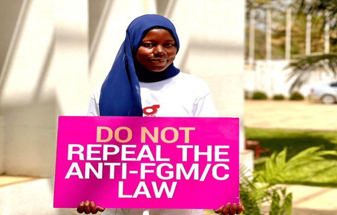 Anti-FGM activist holding a placard calling for the retention of the law banning FGM