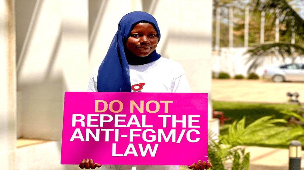 Anti-FGM activist holding a placard calling for the retention of the law banning FGM